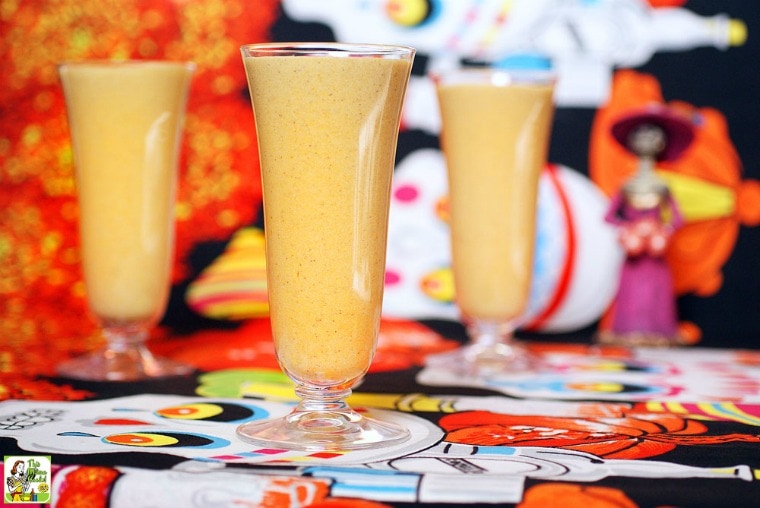 Glasses of pumpkin shake with Day of the Dead figurine and fabric.