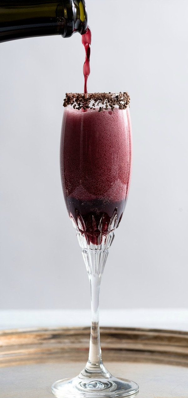 Champagne glass of Sparkling Shiraz Cocktail with Dark Chocolate Coated Cacao Nibs.