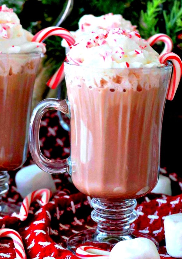 Glass mugs of Spiked Hot Chocolate with candy canes.