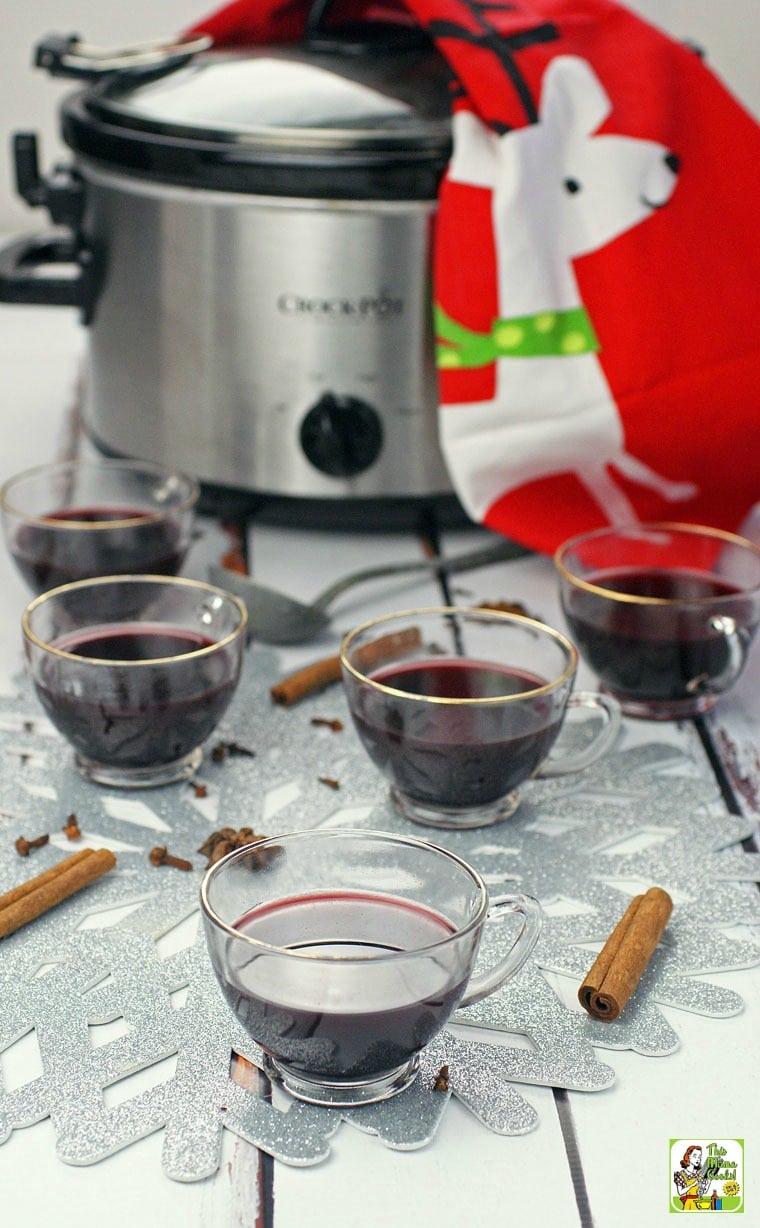 Five glasses of Smoking Bishop and a slow cooker with a holiday tea towel.