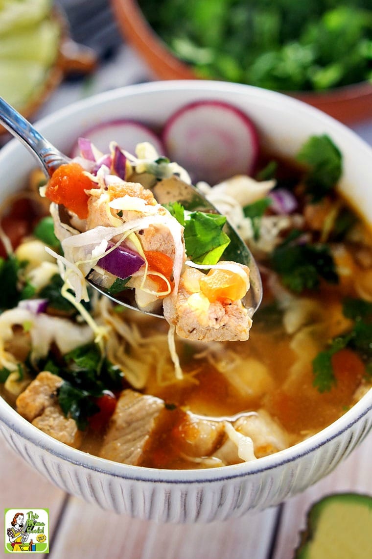 Spoon coming out of a bowl of pozole soup.