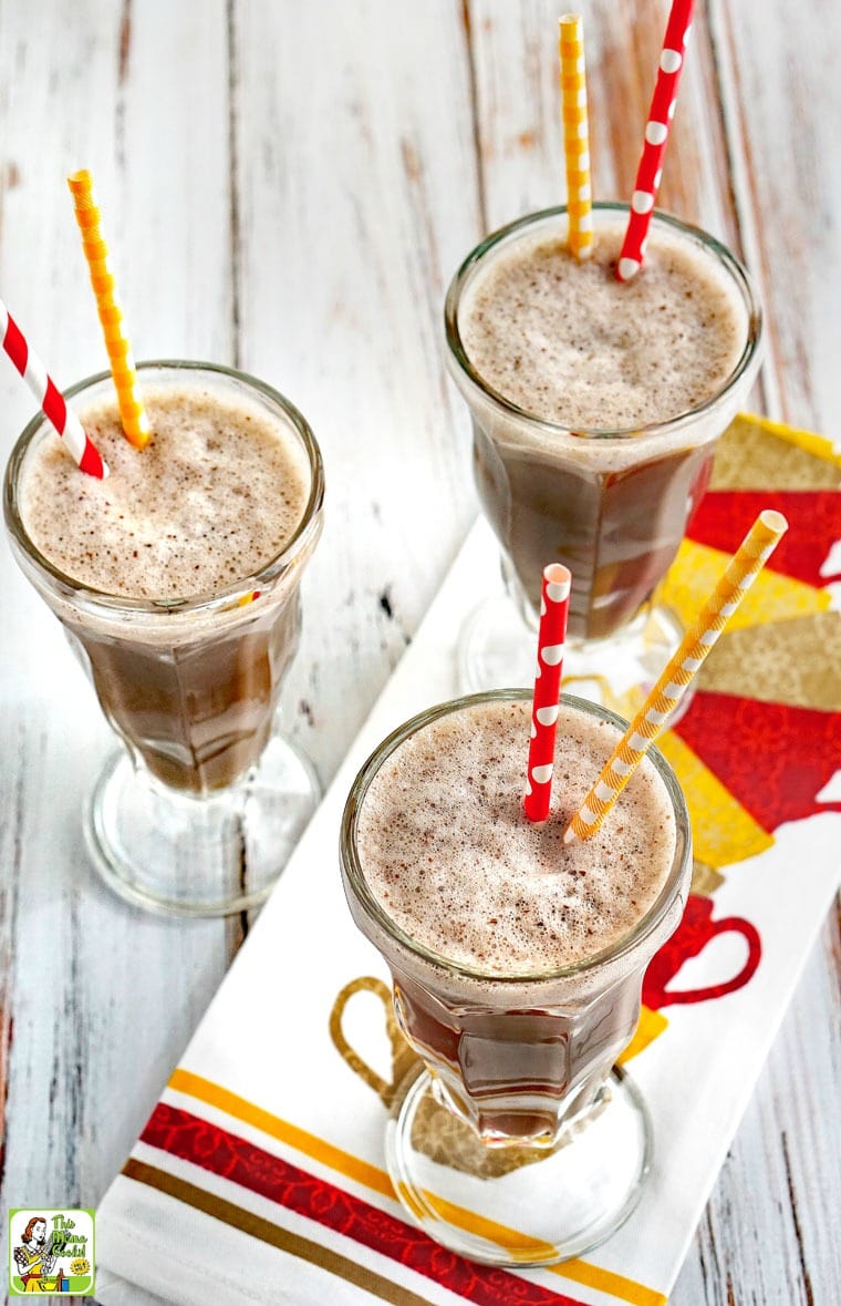 Three tall glasses of Coffee Breakfast Smoothie with yellow and red straws on a colorful tea towel.