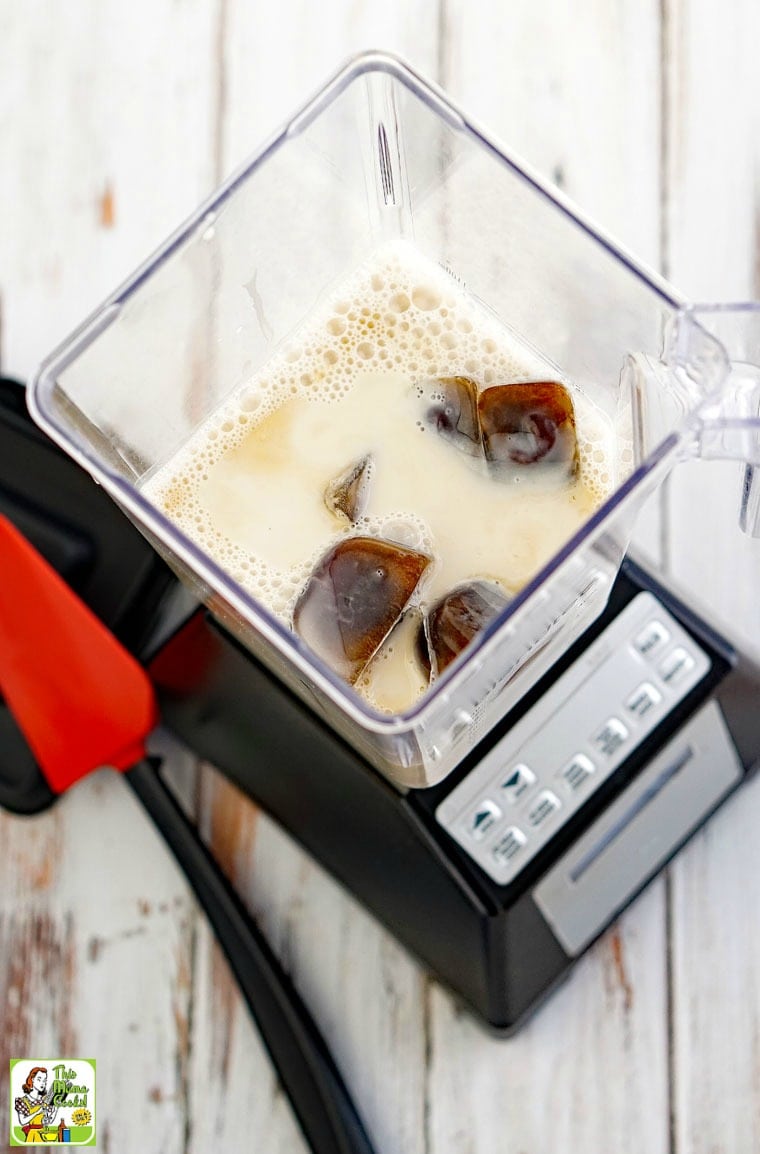 A blender filled with almond milk and cold brew ice cubes for a coffee smoothie drink.