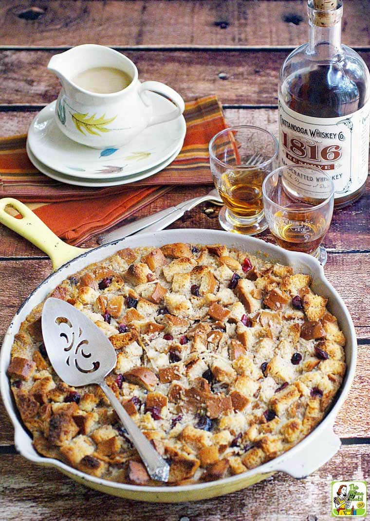 A skillet of bread pudding with glasses of whiskey.