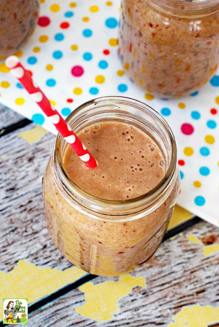 Closeup of an oatmeal smoothie in a mason jar with a red straw with a polka dot tea towel in the background. 