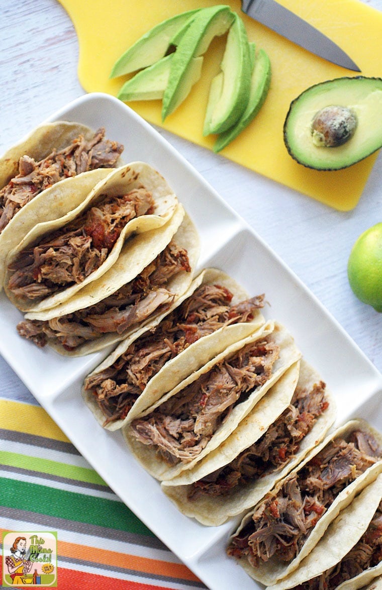 An overhead view of a platter of pulled pork tacos with avocados.