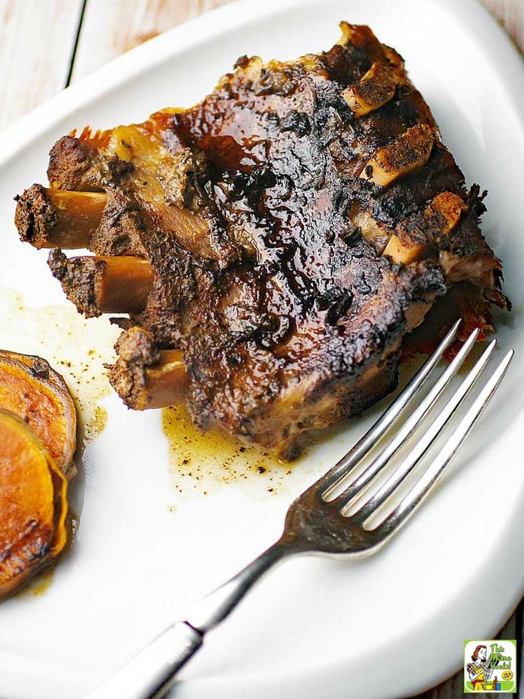 Crock-Pot Ribs with fork on white plate and sliced sweet potatoes.