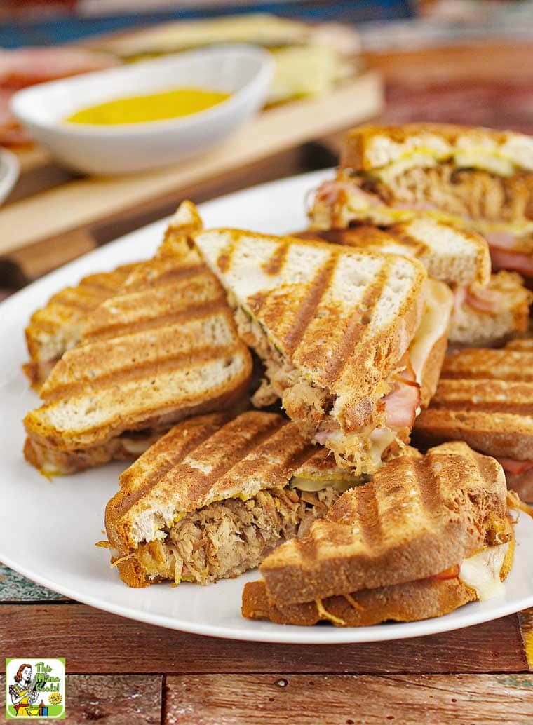 Closeup of a pile of Cuban panini sandwiches on a white platter.