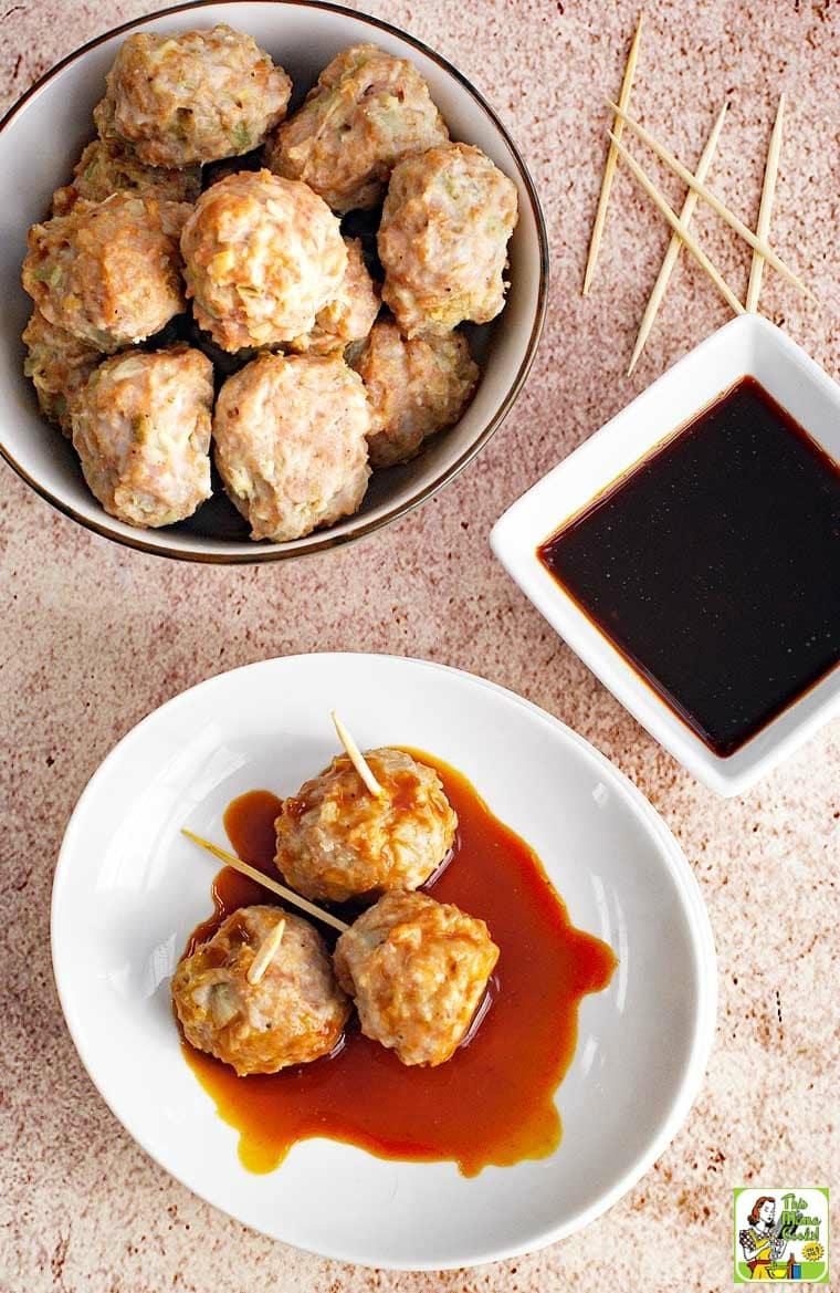 A bowl and plate of Asian style pork meatball appetizers served on toothpicks with a small bowl of dipping sauce.