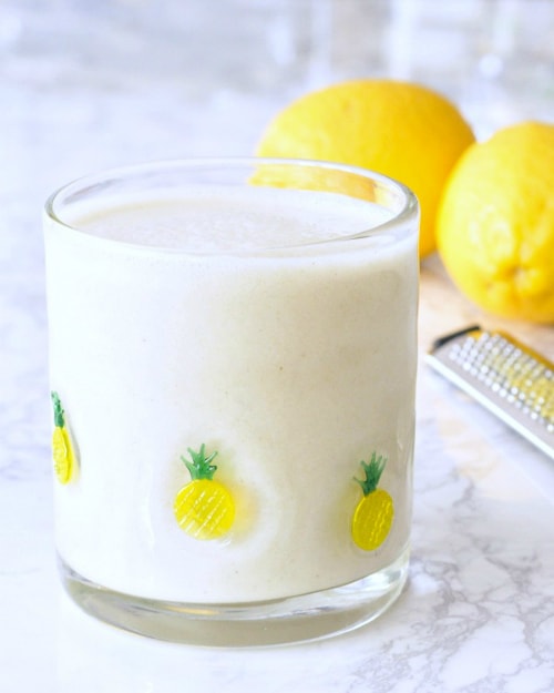 A glass of Light Bright Lemon Smoothie with lemons.