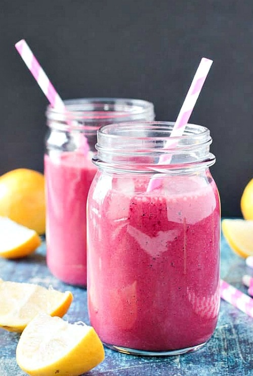 Glasses of Strawberry Beet Smoothie with straws and fruit slices.