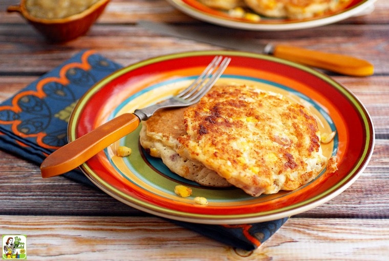 A colorful striped plate with corn fritters, fork, napkin, and knife.