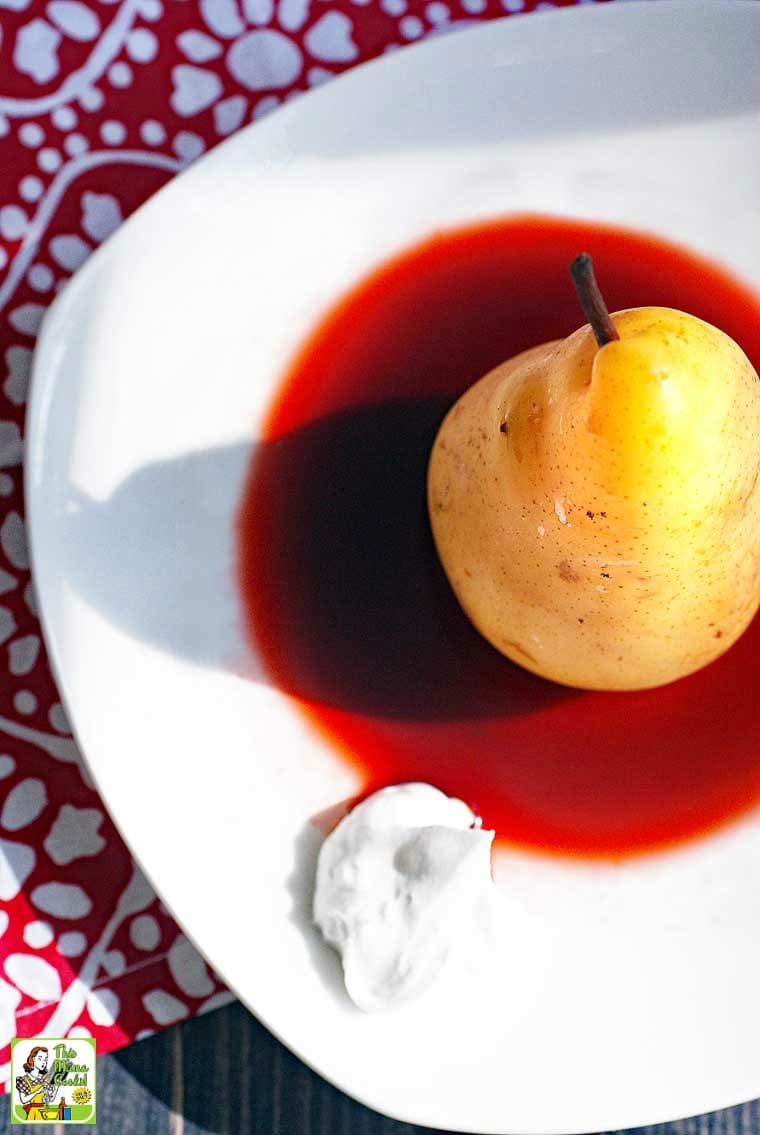 Overhead view of a Poached Pear in cherry sauce with a dollop of coconut whipped cream.