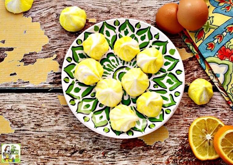 A green plate of Lemon Flavored Meringue Cookies with napkin and sliced lemons.