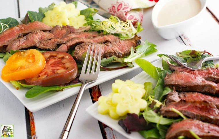 Plates of Flat Iron Steak Salad with Yogurt Dressing with salad and tomatoes and pitcher of dressing.
