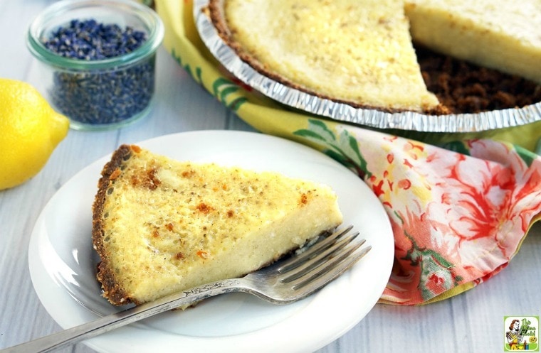 A slice of southern buttermilk pie on a plate with a whole pie in the background on a floral napkin.