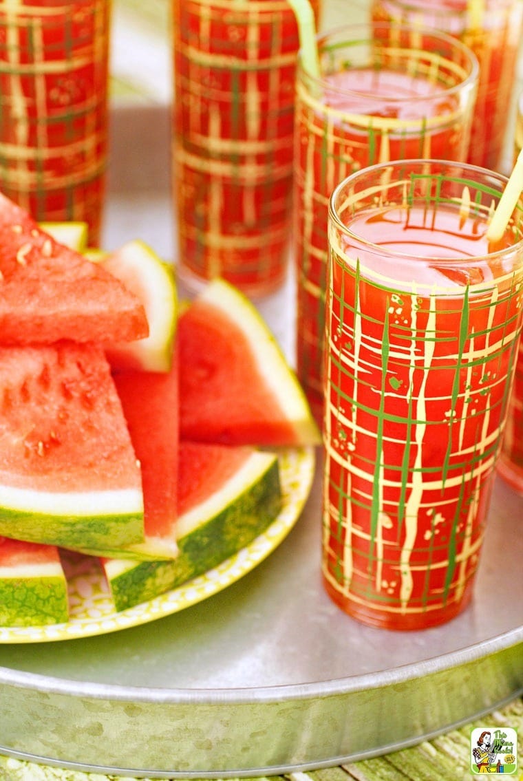 Glasses of watermelon cocktails with a plate of watermelon.