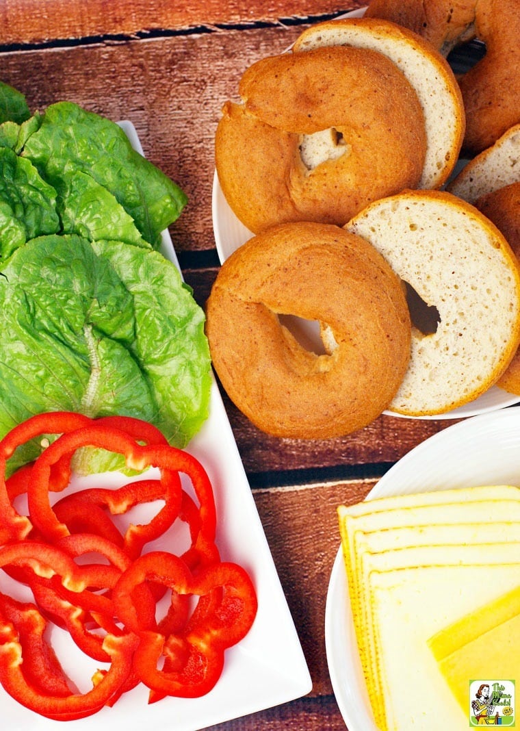 Ingredients for making a bagel burger including bagels, lettuce, cheese, and peppers.