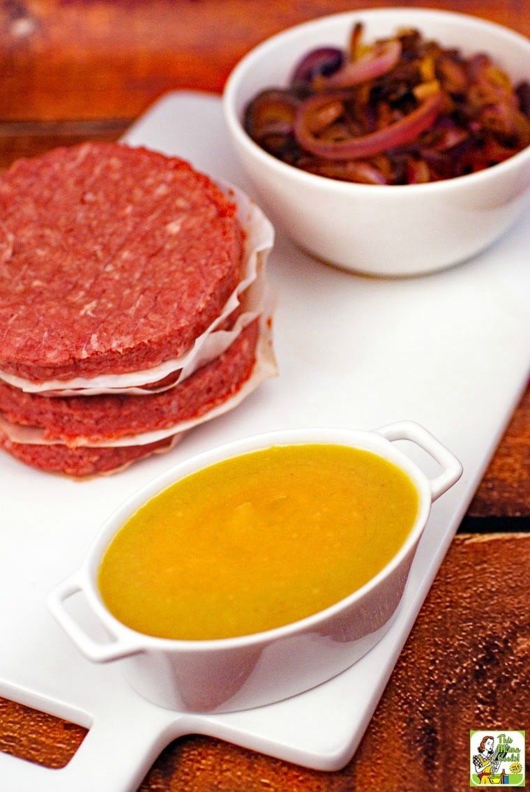 Ingredients for bagel burgers with miso sauce: raw burger patties, onions, and miso sauce in a small ramekin.