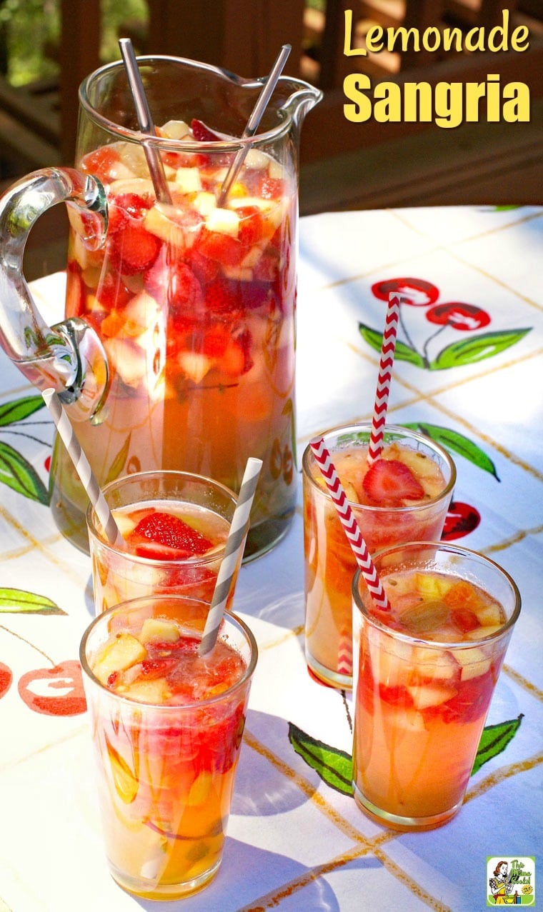 Glasses and a large pitcher of fruit filled Lemonade Sangria with striped straws on a colorful tablecloth.