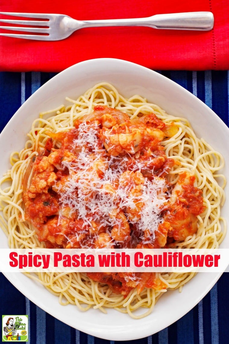 Closeup of Spicy Pasta with Cauliflower in a white bowl on a blue striped tablecloth.