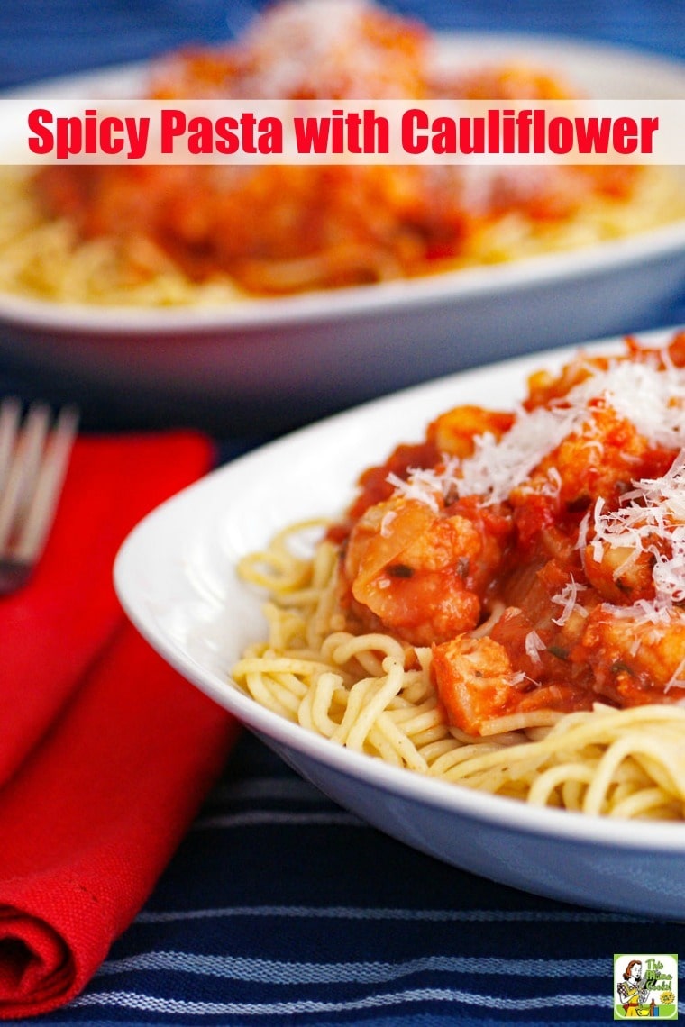 Closeup of Spicy Pasta with Cauliflower in a white bowl with red napkin and fork with another bowl of pasta in the background.