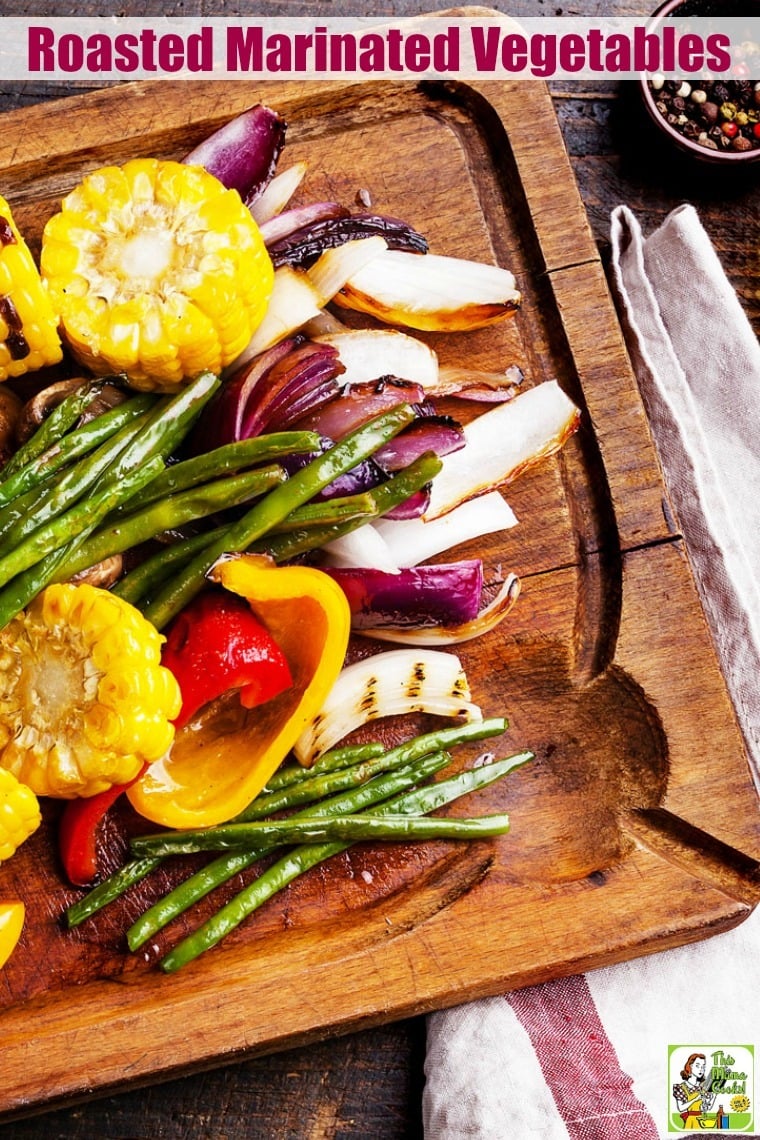 A wooden platter of Roasted Marinated Vegetables with tea towel and peppercorns.