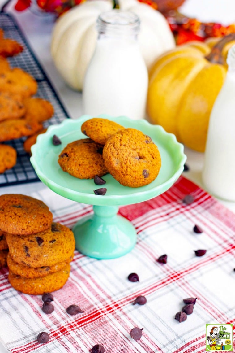 Chocolate Chip Cookies on a green cake stand, baking rack, and a red and white napkin with pumpkins and milk bottles.