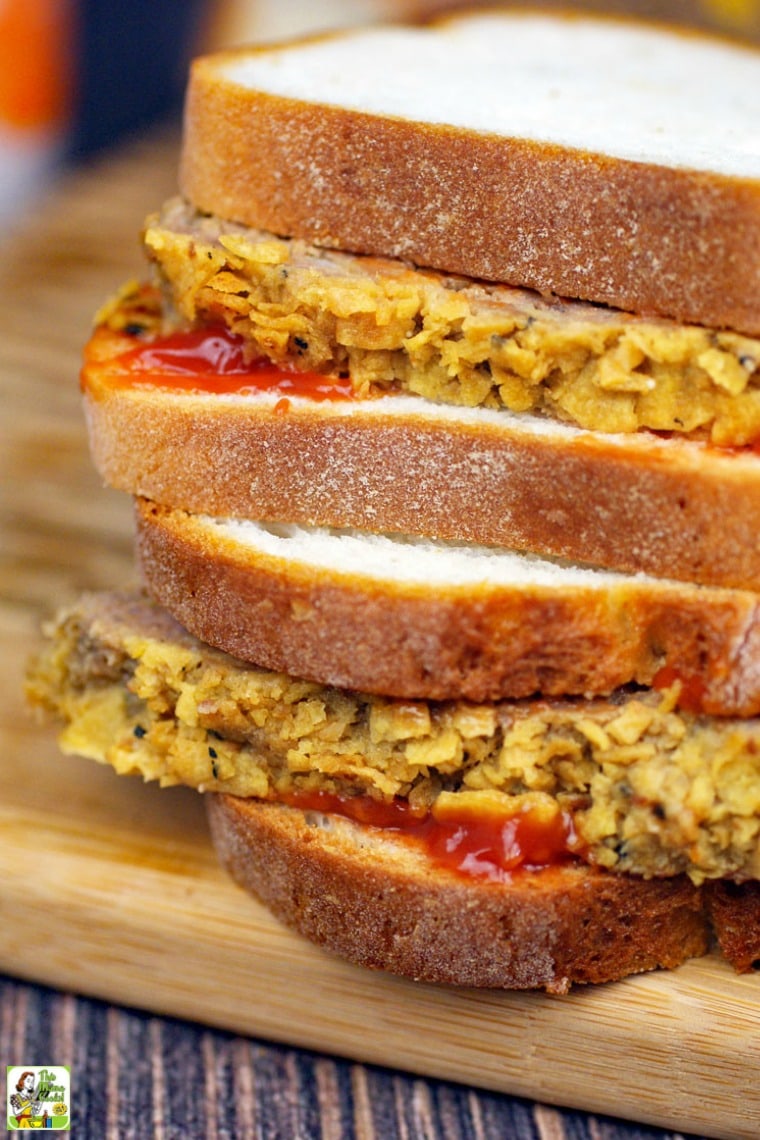 Closeup of a stack of meatloaf sandwiches on a wooden cutting board.
