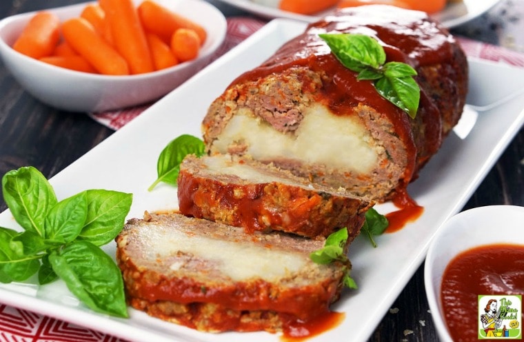 Platter of mashed potato stuffed meatloaf with condiments and carrots.