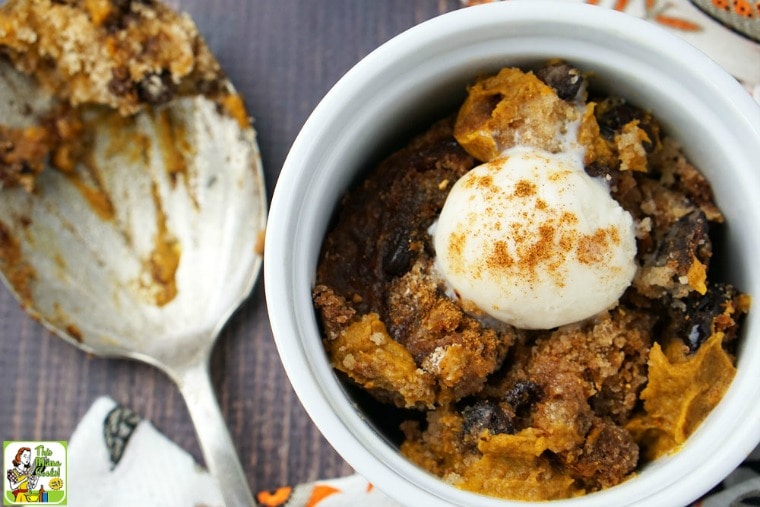 Crockpot Pumpkin Dump Cake with a scoop of ice cream in a white ramekin next to a serving spoon.