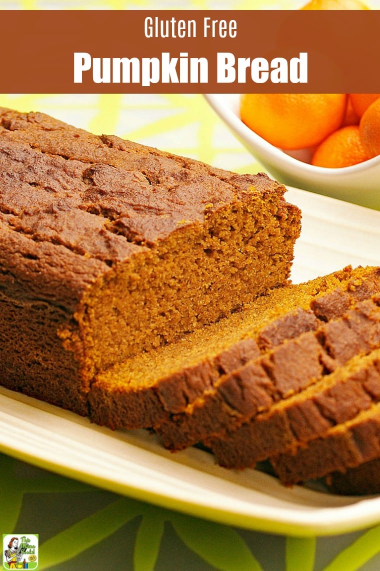 A loaf of  Pumpkin Bread on a white plate with oranges in the background.