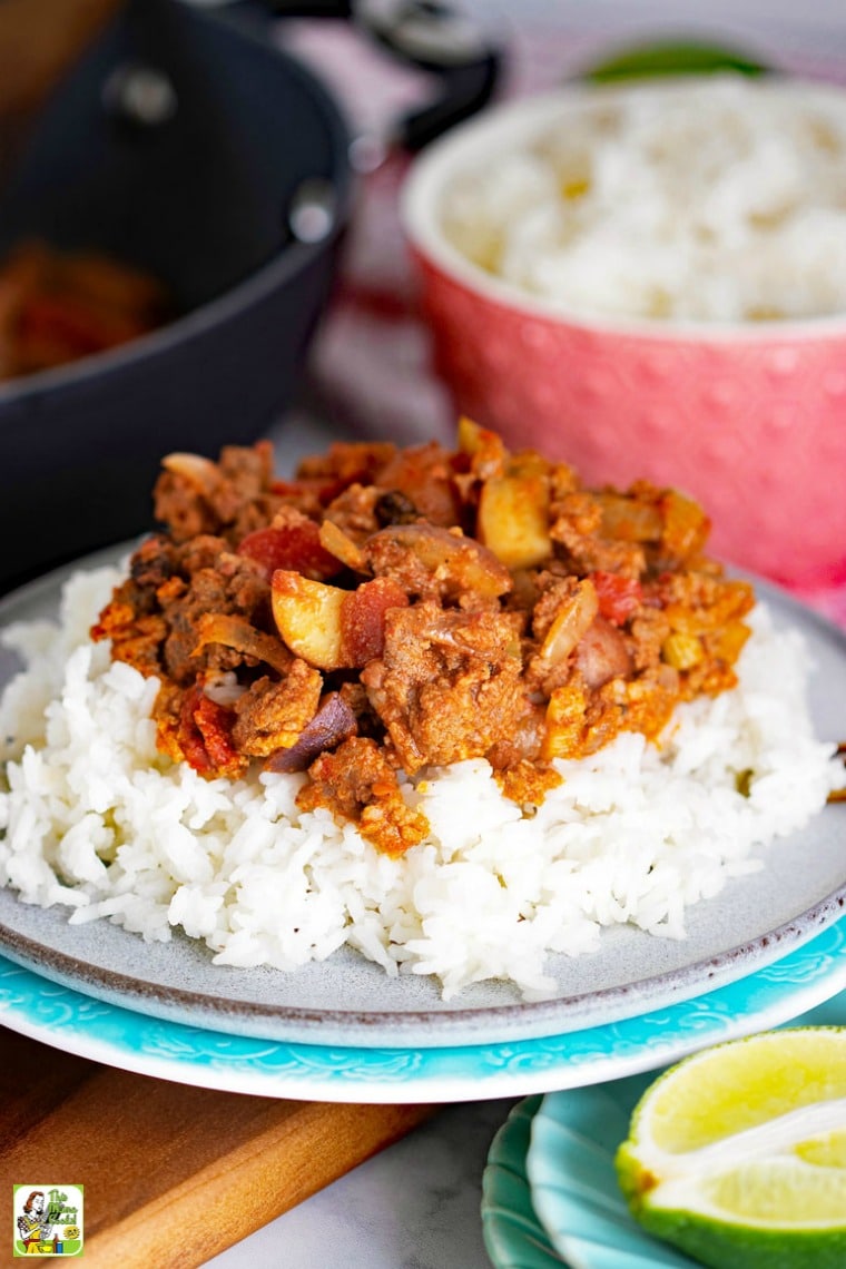 Mexican Picadillo on a plate with white rice, a pink bowl of rice, and a frying pan of picadillo.