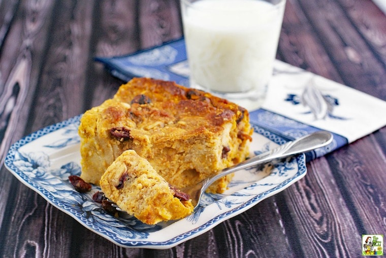 Gluten free bread pudding recipe with pumpkin on a blue and white plate with a fork, glass of milk, and a blue and white napkin.