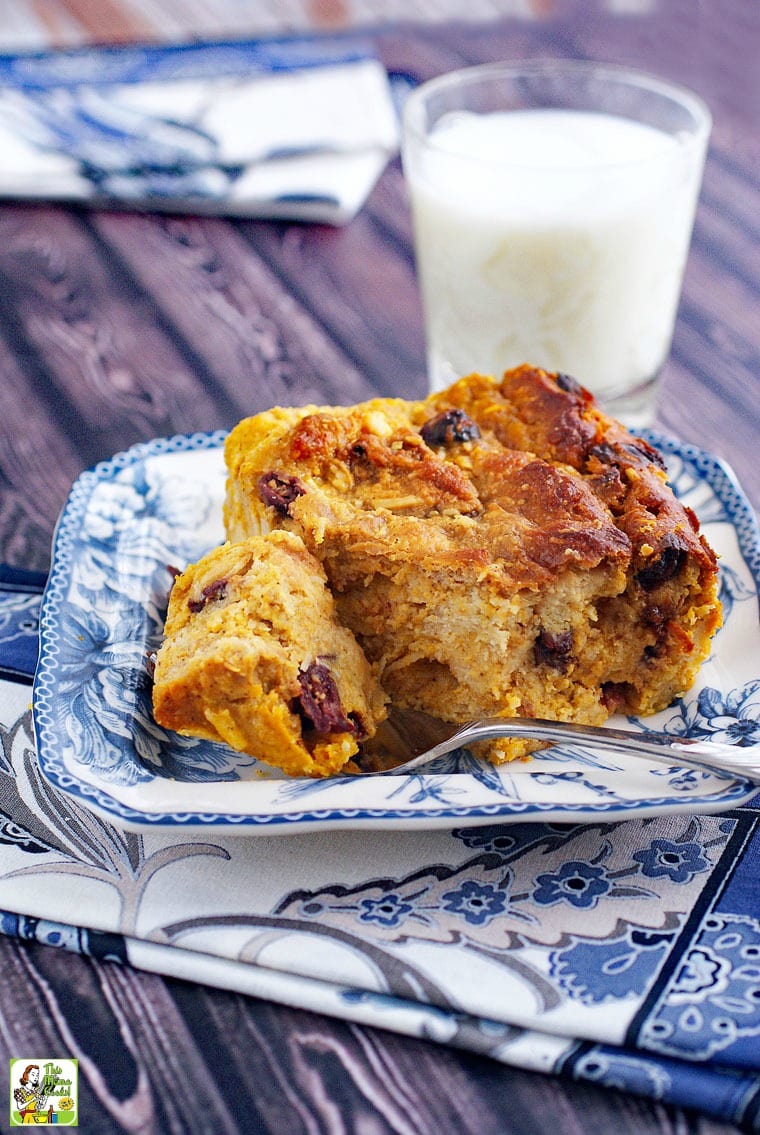 Gluten free bread pudding recipe with pumpkin on a blue and white plate with a fork and a glass of milk and a blue and white napkin.