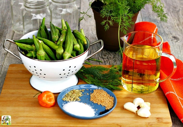Ingredients for making pickled okra including spices, garlic, peppers, herbs, and vinegar.