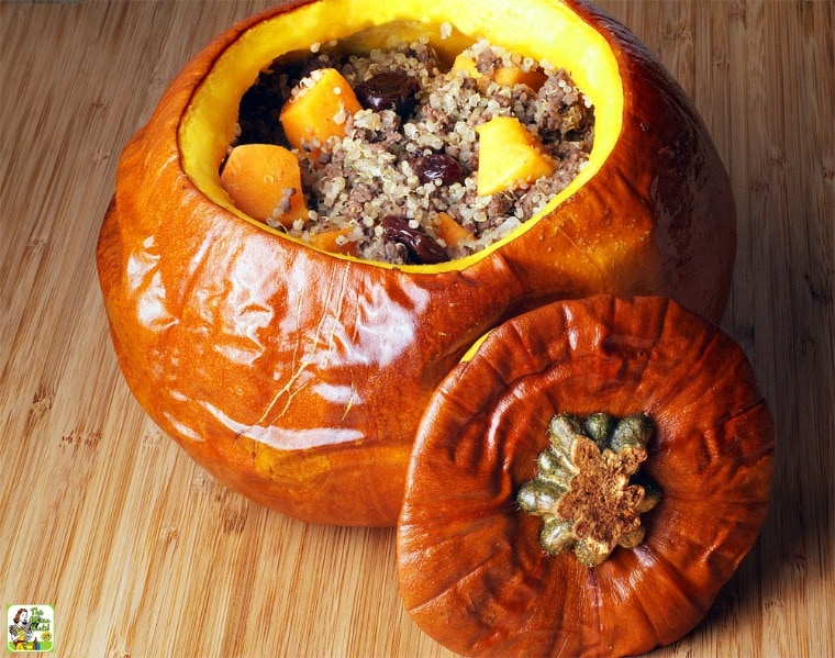 A Quinoa Stuffed Pumpkin with Venison, Cherries & Squash with lid on a wooden tray.