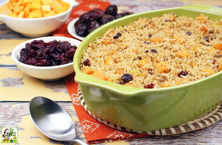 Vegan Rice Stuffing with Cranberries, Squash & Dates in a casserole dish with small dishes of ingredients and a serving spoon.