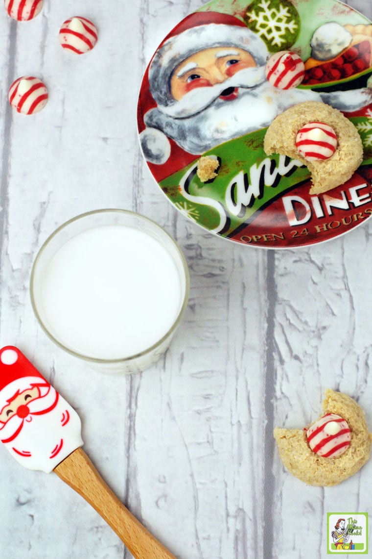 Santa plate of thumbprint cookies with a glass of milk, striped peppermint Hersey's kisses, and a Santa spatula.