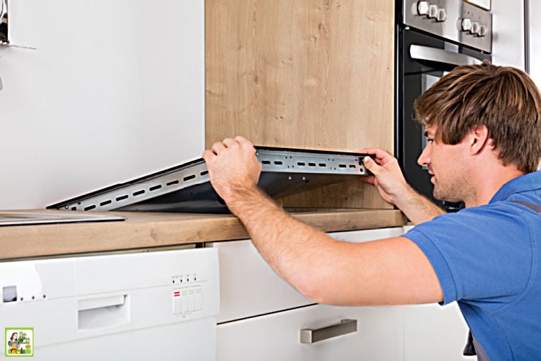 Man in blue shirt installing an induction stove in a kitchen counter.