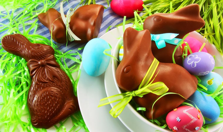 Chocolate Easter bunnies candy and Easter eggs in white plates and bowls.