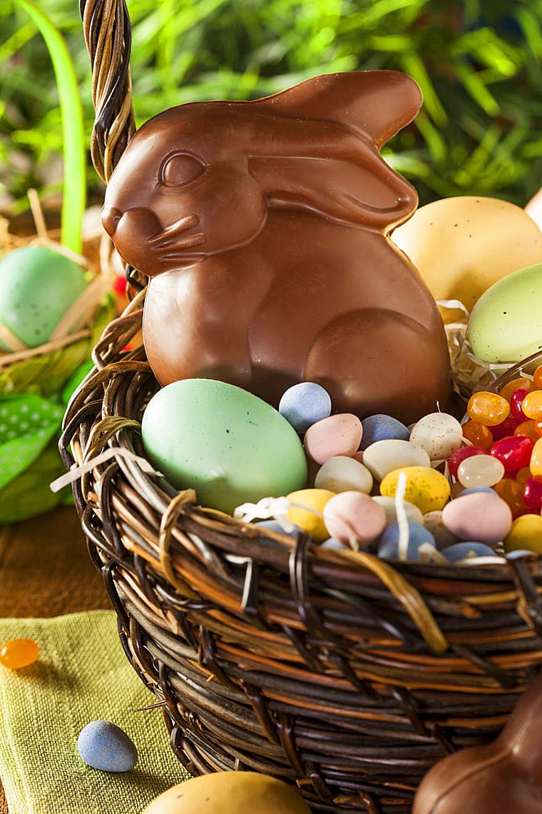 Easter basket with chocolate rabbit, jelly beans, Easter eggs, and candy.