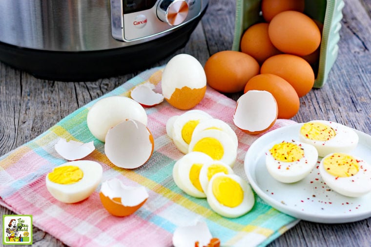 Whole, sliced, and unpeeled Instant Pot hard boiled eggs on a napkin and plate and a pressure cooker in the background.