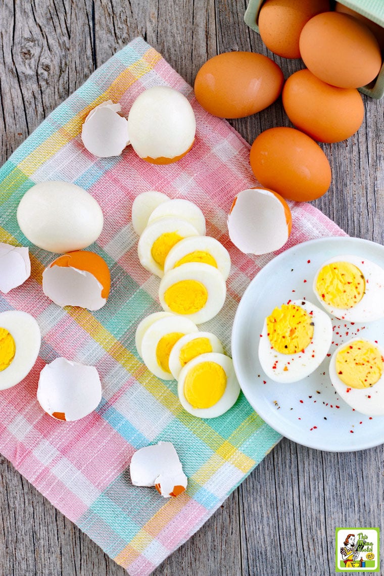 Sliced hard boiled eggs on a white plate and plaid napkin. With white and brown hard boiled eggs in the background.