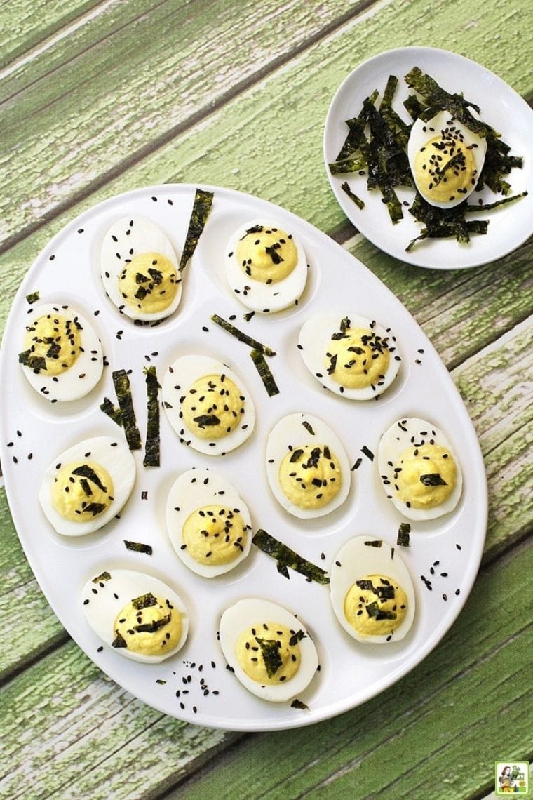 A party appetizer plate of wasabi deviled eggs with sesame seeds and strips of dried seaweed.