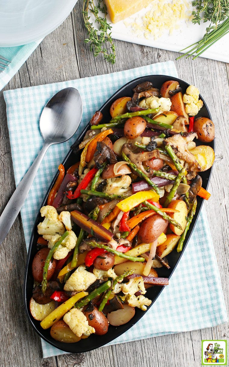 Overhead shot of a platter of roasted vegetables on a napkin with a spoon.