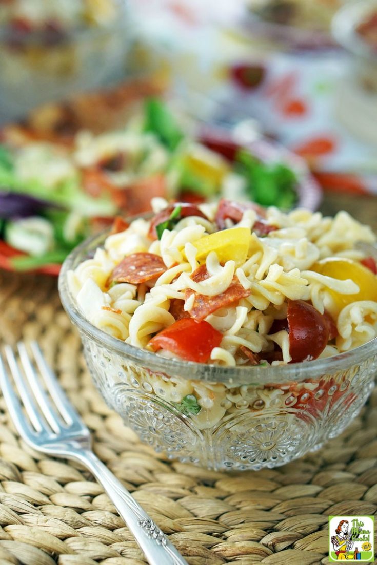 A glass bowl of Caprese Pasta Salad with fork.