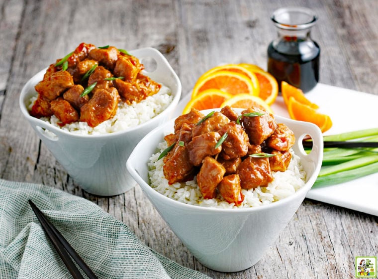 Two bowls of Instant Pot Orange Chicken with rice with a napkin and chopsticks.