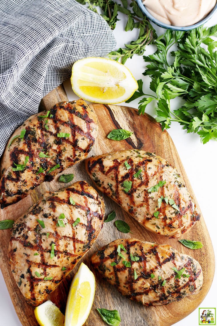 Grilled marinated chicken on a wooden cutting board.