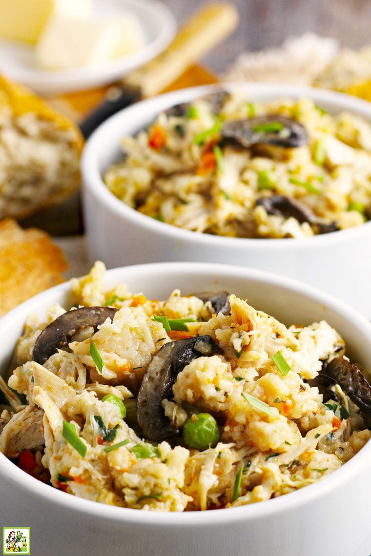 Closeup of bowls of chicken and rice with peas, carrots and mushrooms